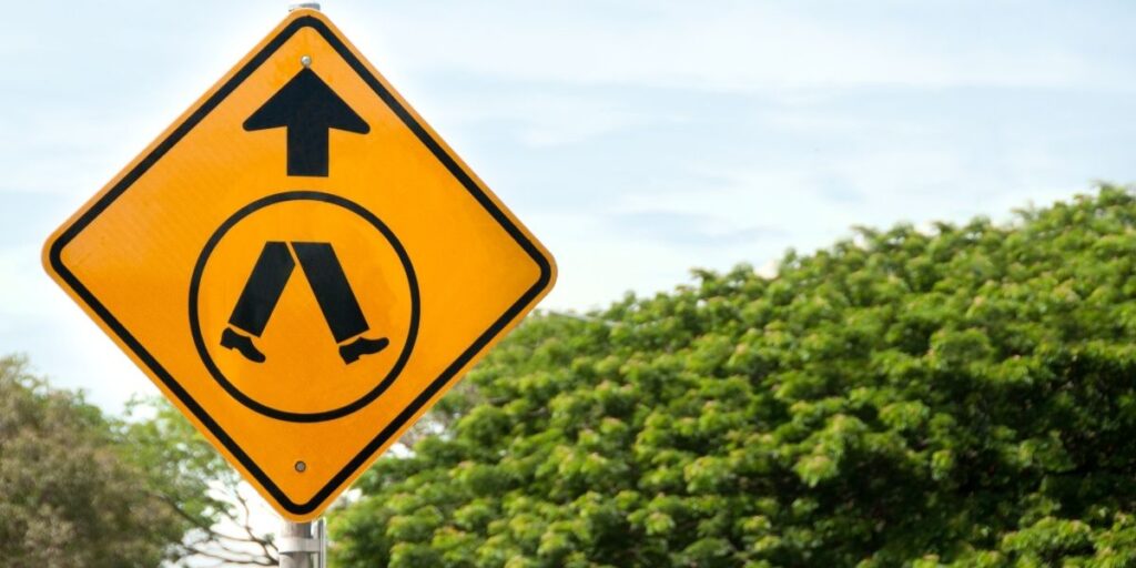 yellow pedestrian sign on the road