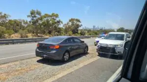 Motor vehicle accident on a Western Australian highway with Perth skyline in background