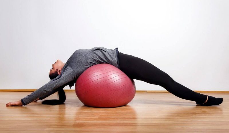 young lady spinal exercise yoga ball