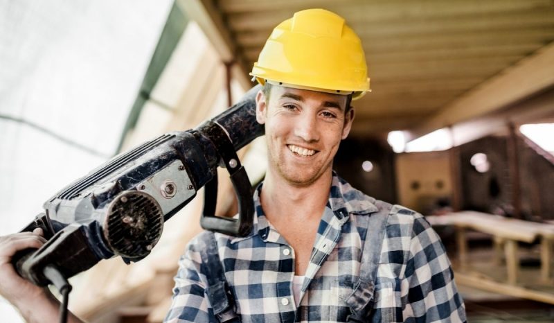 young male worker holding equipment on his shoulder